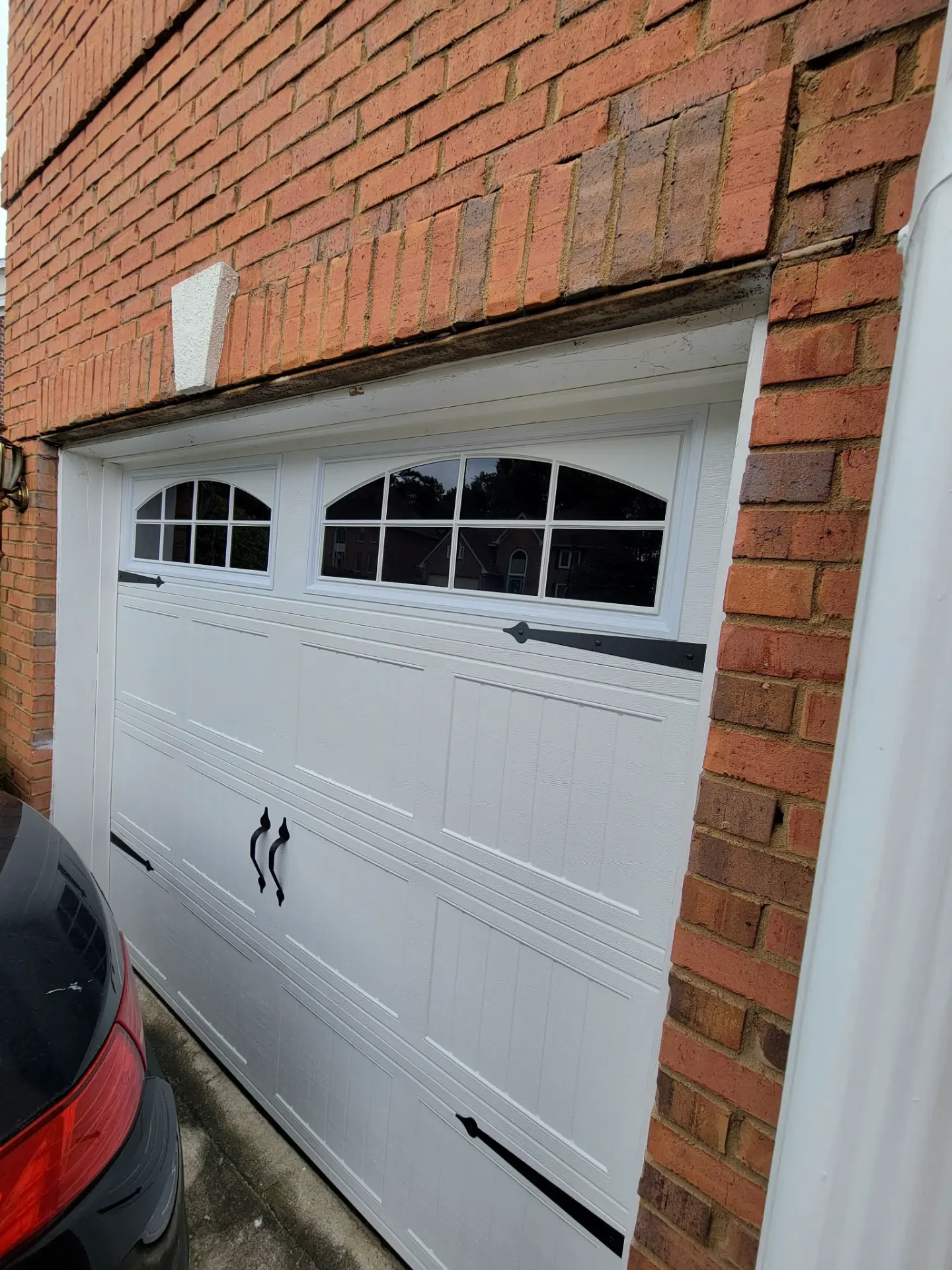 White carriage-house garage door installed in a brick home